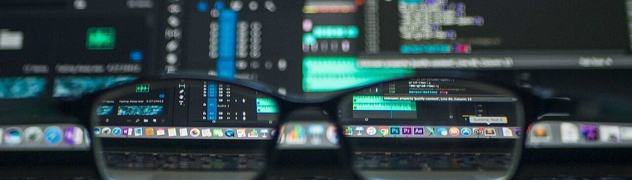 Gafas colocadas delante de un teclado y una pantalla de ordenador.